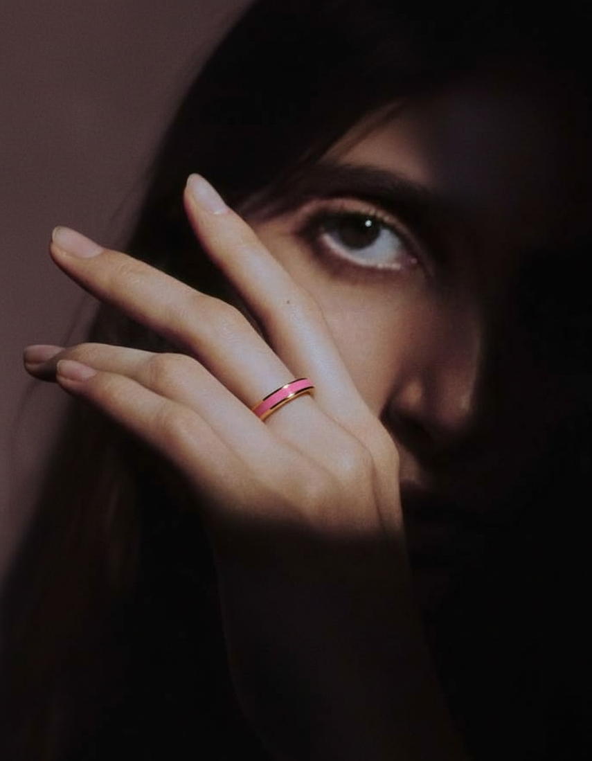 Close-up of a hand with a pink ring on a dark background
