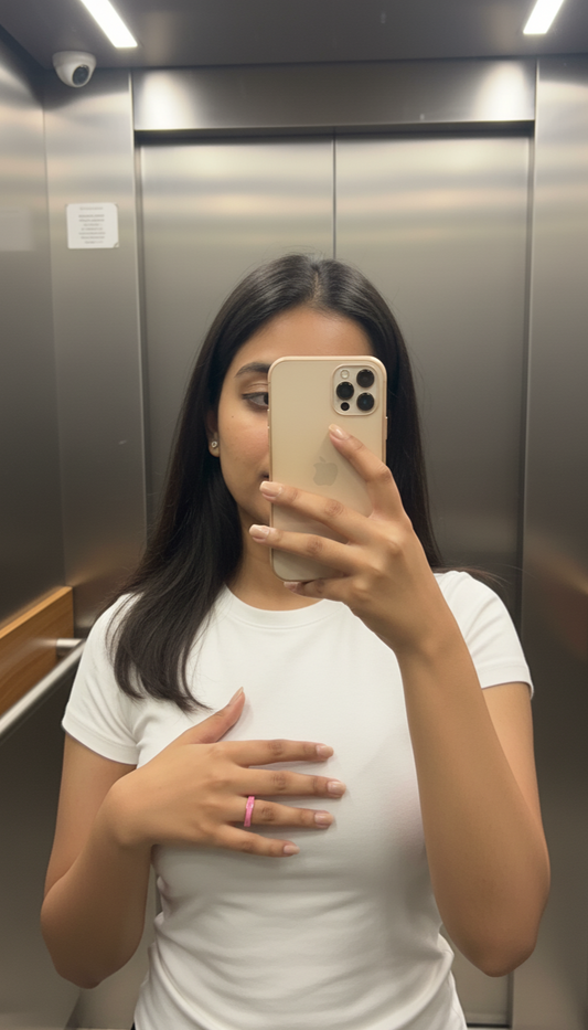 Person taking a mirror selfie in an elevator wearing a white t-shirt.