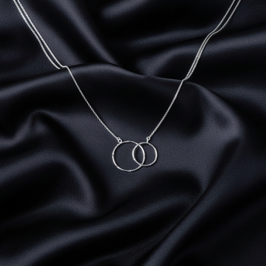 Silver necklace with interlocking rings on black satin fabric
