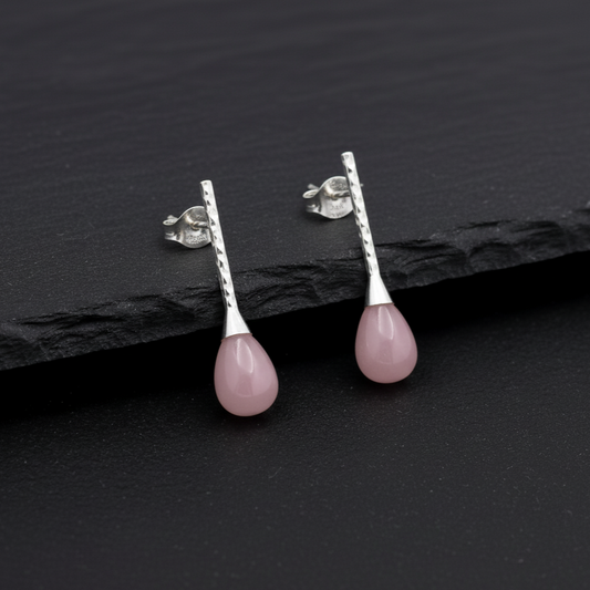 Pink teardrop earrings on a dark slate surface