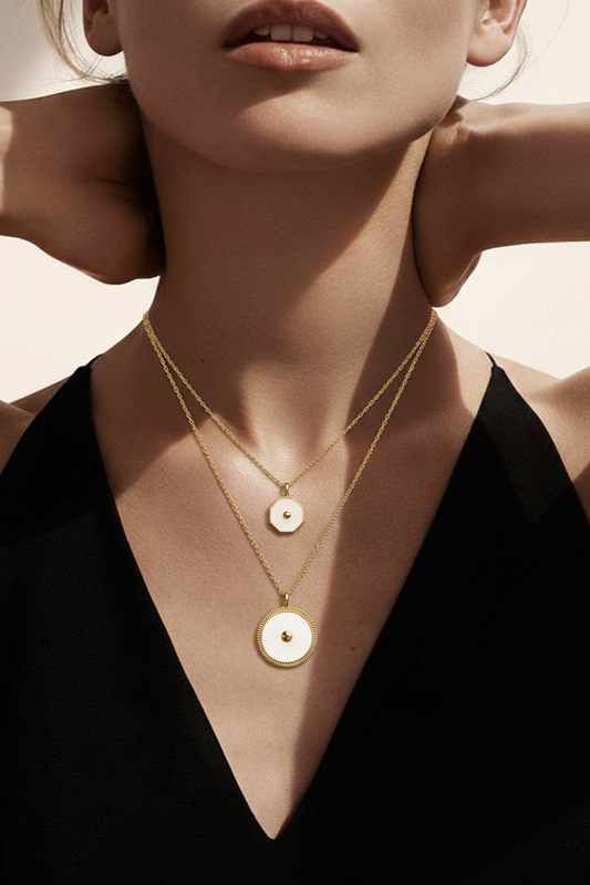 Close-up of a person wearing a gold necklace with circular pendants against a neutral background