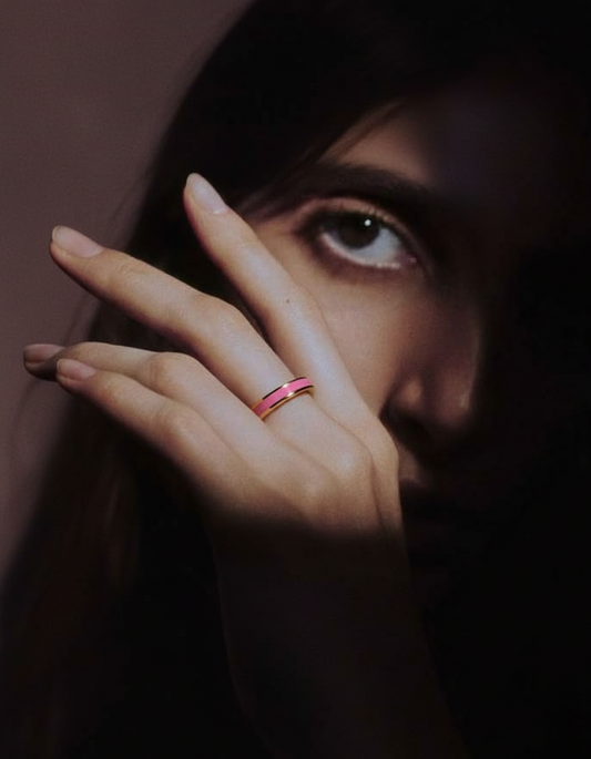 Close-up of a hand with a pink ring on a dark background