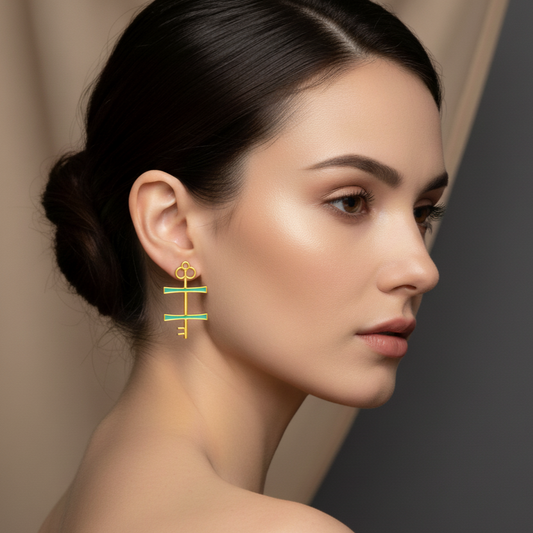 Woman wearing gold and green earrings against a neutral background