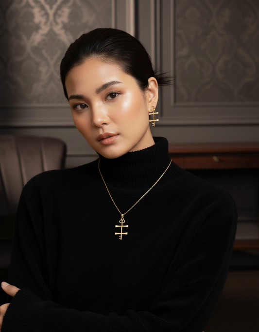 Woman wearing a black turtleneck and gold necklace with a cross pendant in an elegant interior setting.