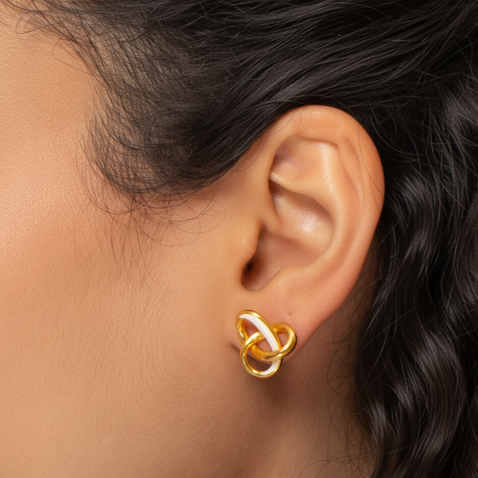 Gold and white earring worn by a person with dark hair.