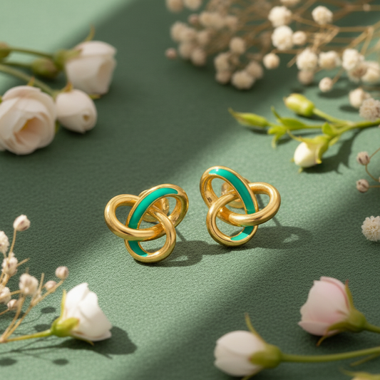 Gold and green knot earrings on a green background with flowers