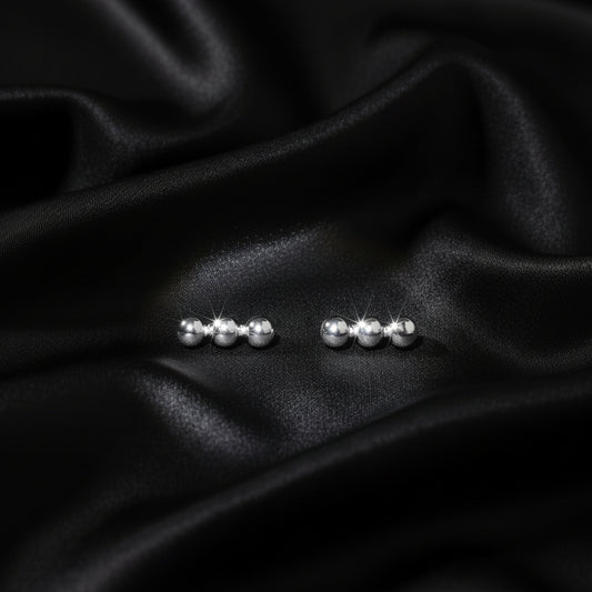 Pair of silver stud earrings on black fabric